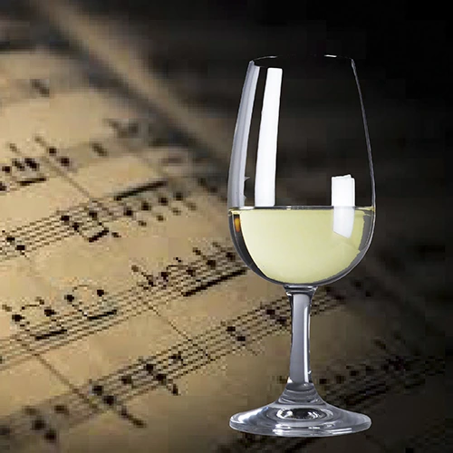 Copa con vino blanco sobre fondo mostrando una partitura musical